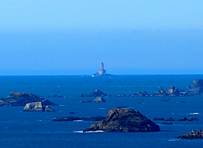 [While the seastack in the foreground are pretty clear in detail, the distance to the lighthouse means the outline edges are softer. However, the skies are clear, so the rock and the round base on which the lighthouse sits are visible.]